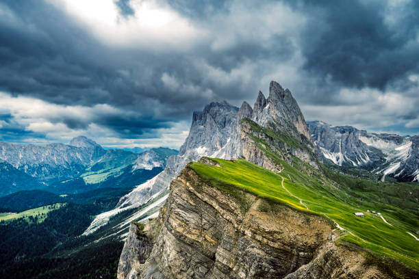 Seceda mountains dramatic cliffs in the Dolomites during an overcast day with a view on the Odle group. The Seceda peak in Dolomites Alps, South Tyrol (Alto Adige), Italy is a populair place to visit for tourists and is accessible by the Seceda Seilbahn from Urtijëi.