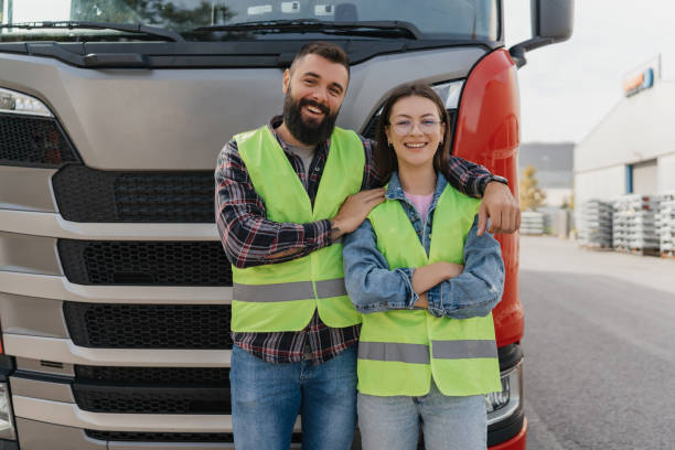 istock Two workers smiling in front of a large truck 2162094694