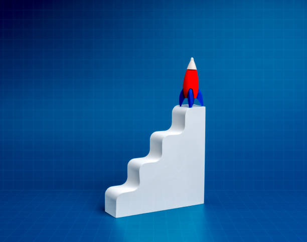 Business startup strategy concept. Red small rocket standing wait for launch, on white modern staircase as a growth graph isolated on blue background with abstract square technology network grid web.