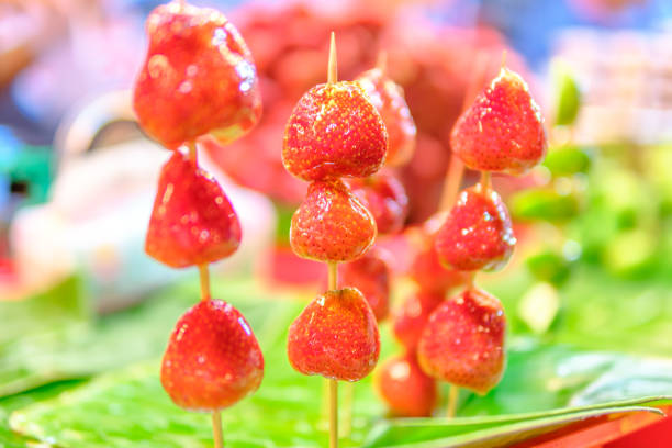 Tanghulu, a popular Chinese street food, featuring green grapes and strawberries covered in a crunchy sugar candy coating