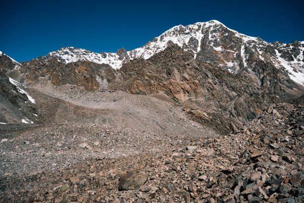 Summer mountain pass crowned by rocks and a snow-topped peak