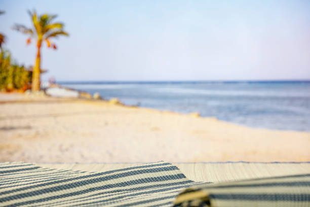 Beach stuff on beach mat on the table with the sea and the tropical beach on background.  Travel and vacation concept.