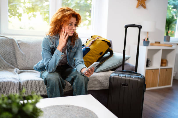 istock Caucasian female tourist, using a mobile phone while arriving with a suitcase at a vacation rental unit 2162100033