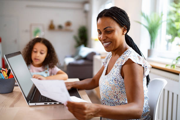 istock Woman Black ethnicity working on laptop while her daughter doing her homework 2162100159