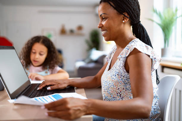 istock Mother Black ethnicity working on laptop while her daughter doing her homework 2162100167