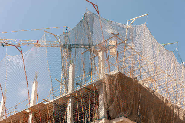 Captivating image of construction site under a bright sky, featuring crane, safety nets, and framework, ideal for themes related to urban development, construction safety, and architectural projects.