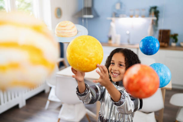 Curious and playful multiracial girl in a space suit, playing with handmade planets