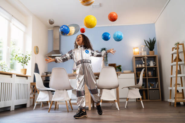 istock Playful multiracial girl in a space suit playing with handmade planets 2162100620