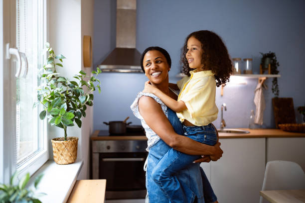 istock Mother Black ethnicity holding her daughter while both looking through the window 2162100621
