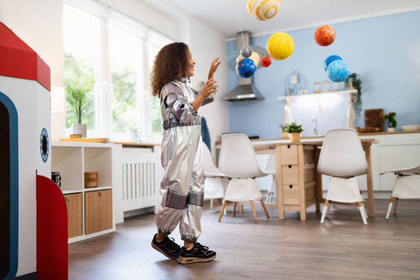 istock Playful multiracial girl in a space suit playing with handmade planets 2162100624