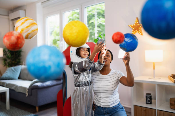 istock Multiracial girl in a space suit, exploring and learning about planets with her mother 2162101196