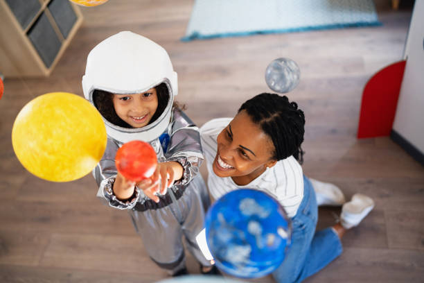 Curious girl in a space suit, exploring and learning about planets with her mother