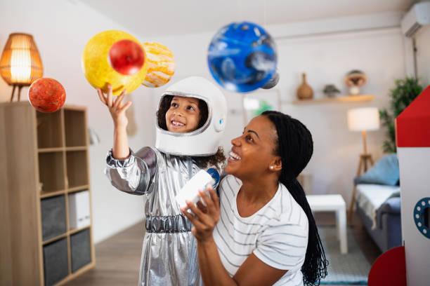 istock Multiracial girl in a space suit, exploring and learning about planets with her mother 2162101211