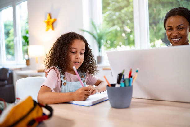 istock Multiracial girl doing her homework, while her mother working on laptop from home 2162101353