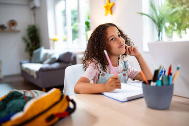 Multiracial girl doing her homework, at home for the dining table
