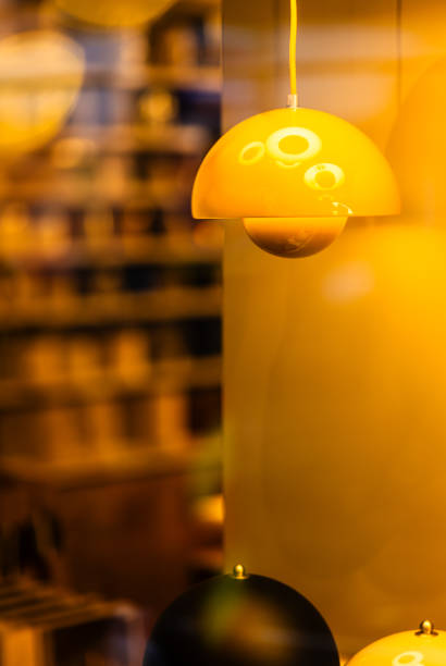 An abstract composition where a stunning yellow lamp hangs gracefully from the ceiling, casting warm light. Below it, two additional lamps stand out: a sleek black lamp positioned in the center of the frame, and a second yellow lamp nestled in the lower right corner. The intentional defocusing adds an artistic touch, emphasizing the contrast between the vibrant yellow and the dark black.