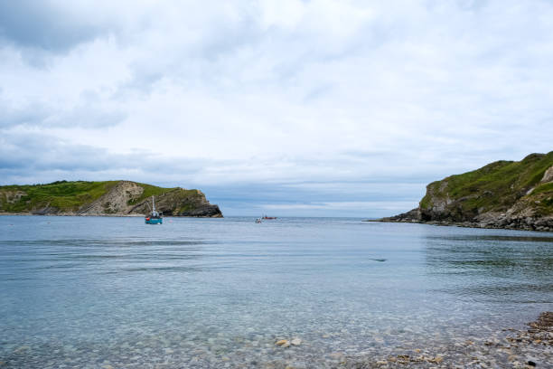 Lulworth cove bay from the beach. Small fisherman boats in the sea. Lulworth Cove bay and cliffs view . The Jurassic Coast is a World Heritage Site on the English Channel coast of southern England. Dorset, UK.