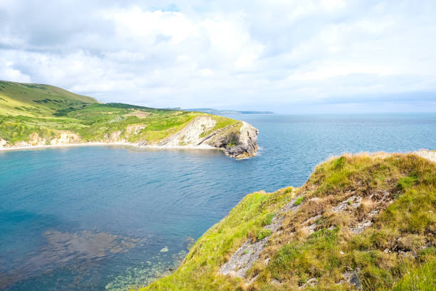 Dramatic Rocky Coastal Cliff with Clear Turquoise Sea and Overcast Sky along the Rugged Shoreline