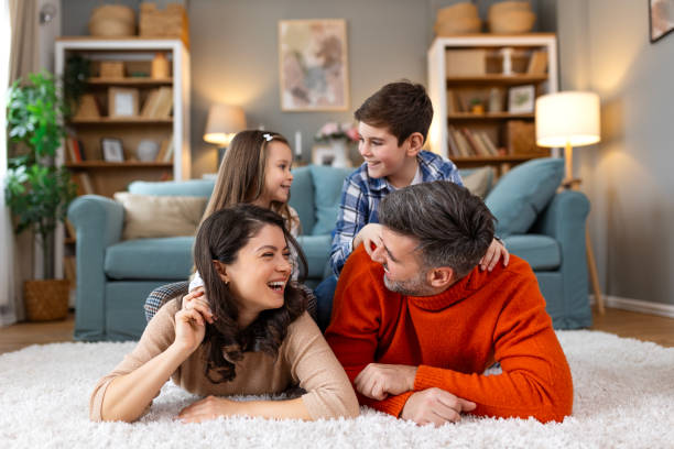istock Happy parents and their small kids talking while lying on carpet at home. 2162112277