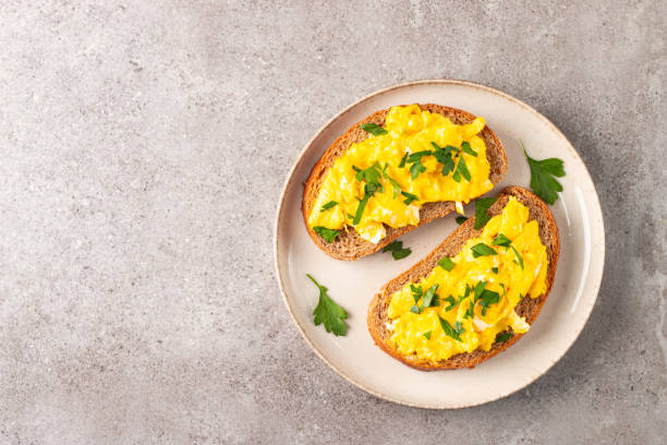 istock Scrambled eggs with green herbs on wheat-rye crispy toast. 2162112447