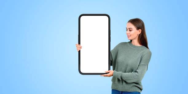 istock A woman holding a large, blank smartphone mockup with a white di 2162113390