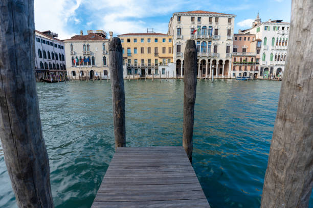 Venice, Italy - June 03, 2024: empty narrow pier in Venice canal. Paline, briccole (typical poles near the pontoon)