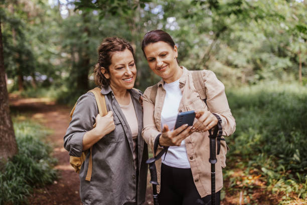 istock Two women looking at a device in forest, smiling happily 2162115656