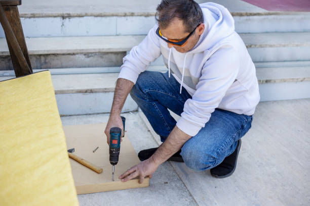 Man in protective eyewear using power drill outdoors