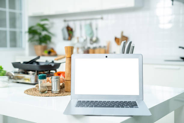 istock Mockup of laptop computer with empty screen sugar, spices in glass jars eggs, vegetable,tomato and a whisk on the kitchen on white table. Flat lay. Concept of food preparation, on background. 2162116369