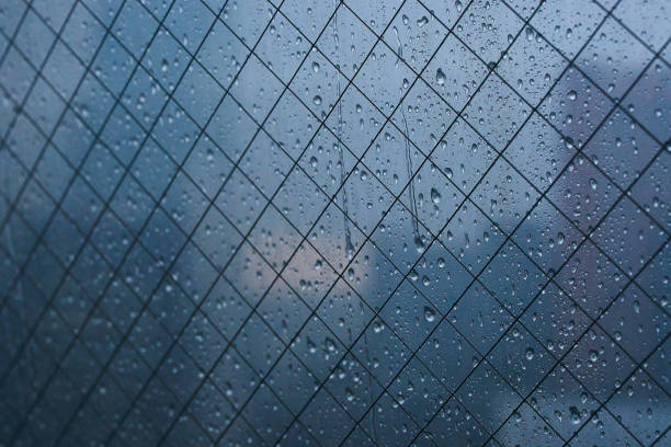 Raindrops on window glass surface. Blurred background.