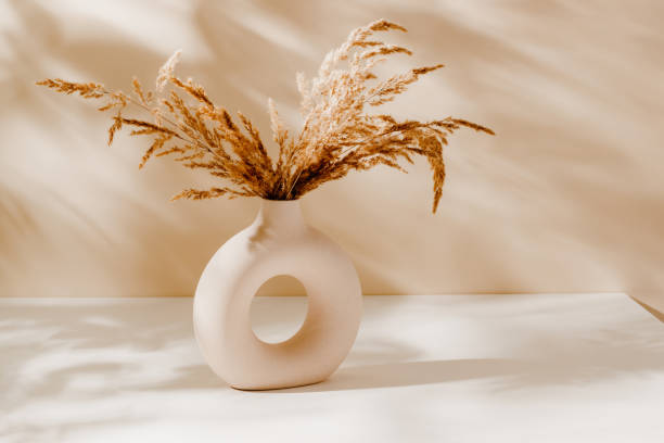 istock Ceramic stylish vase with pampas grass bouquet and sunlight shadows on brown background 2162116848