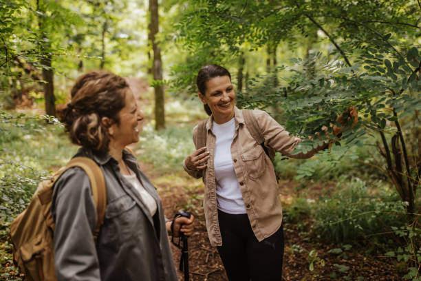 istock Two women hiking, one points towards foliage in forest. 2162117332