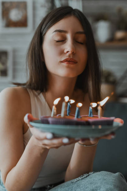 istock Female Making A Birthday Wish Before Blowing The Cupcake Candles 2162117970