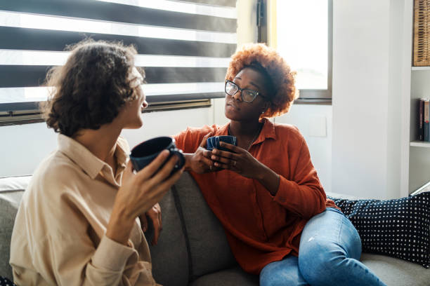 Two young women having a serious conversation on the couch at home