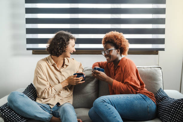 istock Two young women are laughing and chatting on a comfortable sofa 2162118094
