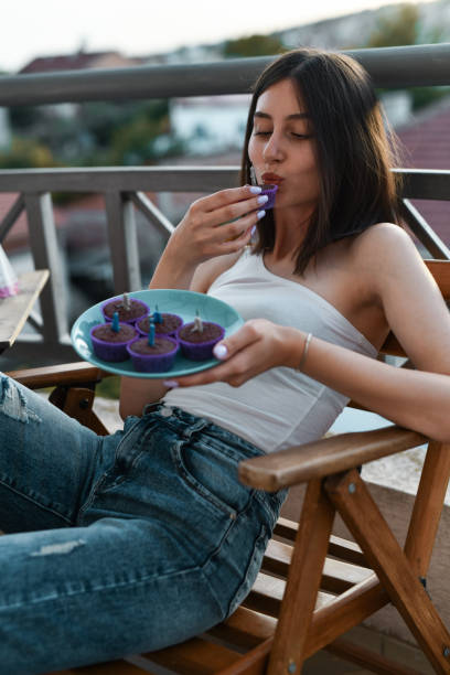 istock Female Eating Delicious Cupcakes On Balcony During Sunset 2162118521