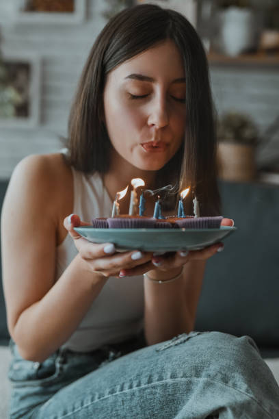 istock Female Making A Wish And Blowing Birthday Candle Fire From Cupcakes 2162118675