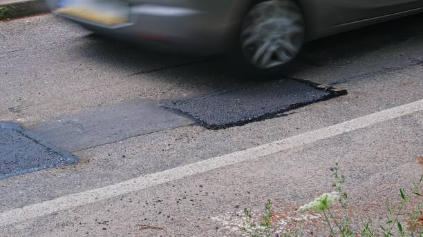 istock Car Driving over Street Surface Pothole Repaired with Fresh Asphalt Patch 2162118774