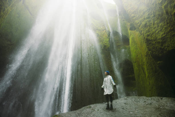istock Happy Woman Contemplating Dramatic Waterfall Hidden in Cave 2162118810