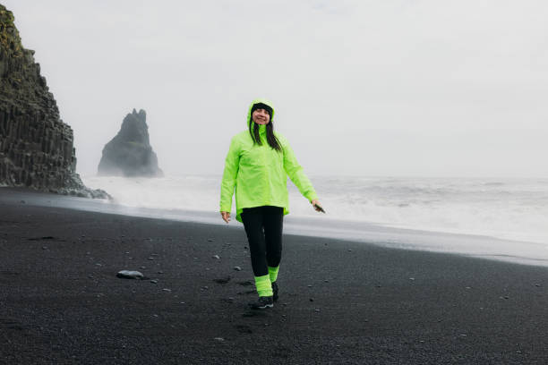 istock Happy Mature Traveller Walking at Dramatic Black Sand Beach Admiring Ocean Views 2162118830