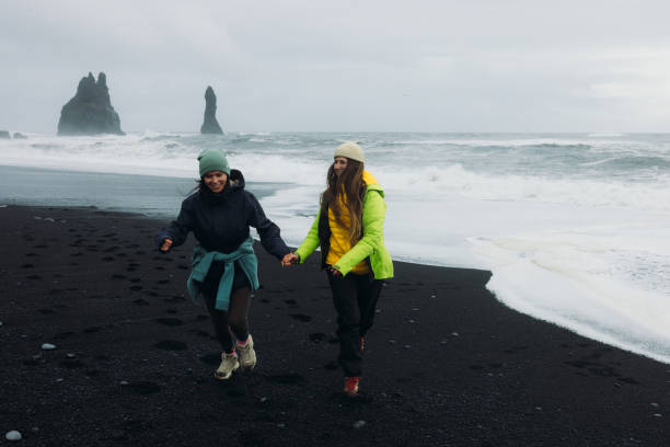 istock Two Happy Travellers Running at Dramatic Black Sand Beach With Ocean Views in Iceland 2162118965