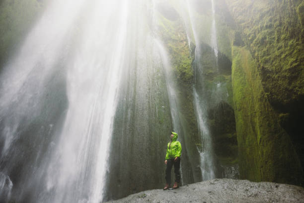 istock Happy Traveller Contemplating Dramatic Waterfall Hidden in Cave in Iceland 2162119019