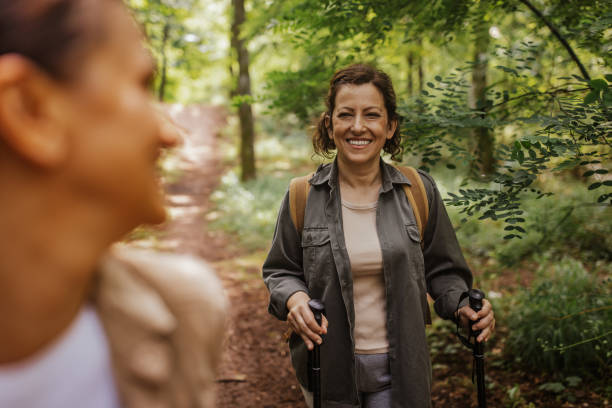 istock Two friends enjoying hike in forest with hiking poles 2162120353