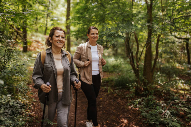 istock Two women hiking through shaded forest path, trekking poles 2162120506