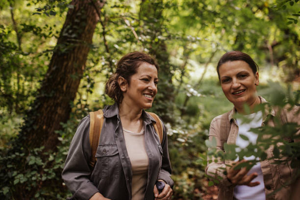 istock Two women hiking in forest with backpacks and sticks 2162120636