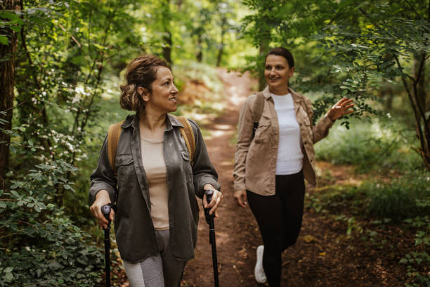 istock Two women hiking in lush green forest, using trekking poles 2162120669