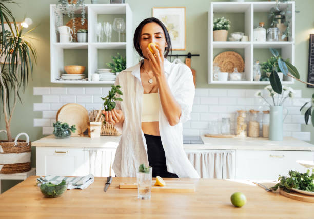 istock A young attractive woman makes delicious fresh lemonade and sniffs lemon and mint. 2162120741