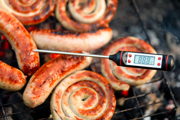 Close-up shot of grilled sausages on barbecue with digital thermometer showing temperature in Celsius template