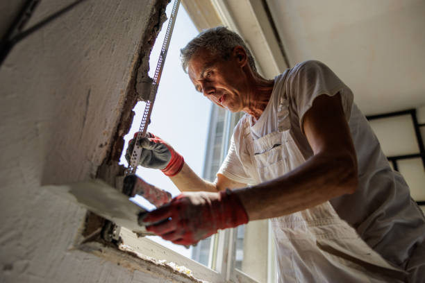 istock Mature craftsperson plastering wall around new window 2162124093