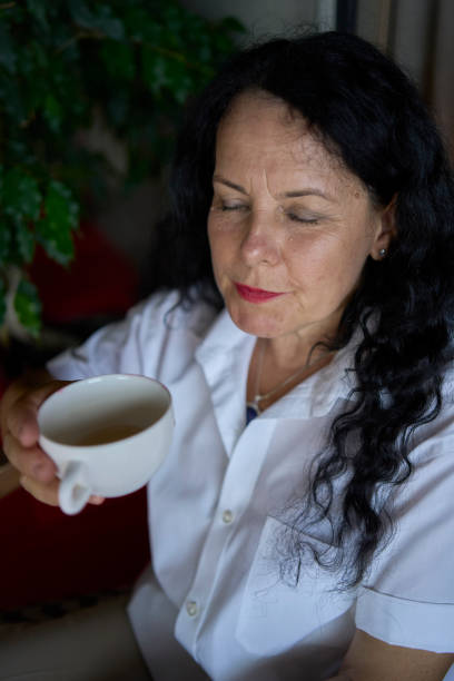 istock 60s woman drinking nettle tea in modern coworking office during lunch break 2162125134